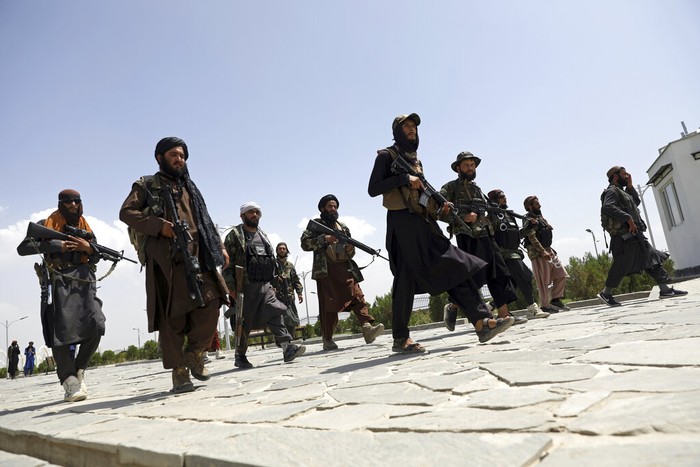 Taliban fighters patrol as two Traffic policemen stand, left, in Kabul, Afghanistan, Thursday, Aug. 19, 2021. The Taliban celebrated Afghanistans Independence Day on Thursday by declaring they beat the United States, but challenges to their rule ranging from running a country severely short on cash and bureaucrats to potentially facing an armed opposition began to emerge. (AP Photo/Rahmat Gul)