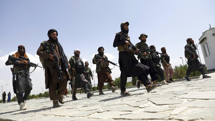 Taliban fighters patrol as two Traffic policemen stand, left, in Kabul, Afghanistan, Thursday, Aug. 19, 2021. The Taliban celebrated Afghanistans Independence Day on Thursday by declaring they beat the United States, but challenges to their rule ranging from running a country severely short on cash and bureaucrats to potentially facing an armed opposition began to emerge. (AP Photo/Rahmat Gul)