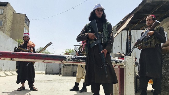 Taliban fighters patrol as two Traffic policemen stand, left, in Kabul, Afghanistan, Thursday, Aug. 19, 2021. The Taliban celebrated Afghanistans Independence Day on Thursday by declaring they beat the United States, but challenges to their rule ranging from running a country severely short on cash and bureaucrats to potentially facing an armed opposition began to emerge. (AP Photo/Rahmat Gul)