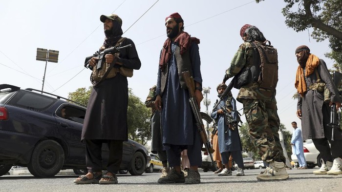 Taliban fighters patrol as two Traffic policemen stand, left, in Kabul, Afghanistan, Thursday, Aug. 19, 2021. The Taliban celebrated Afghanistans Independence Day on Thursday by declaring they beat the United States, but challenges to their rule ranging from running a country severely short on cash and bureaucrats to potentially facing an armed opposition began to emerge. (AP Photo/Rahmat Gul)
