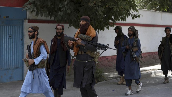 Taliban fighters patrol as two Traffic policemen stand, left, in Kabul, Afghanistan, Thursday, Aug. 19, 2021. The Taliban celebrated Afghanistans Independence Day on Thursday by declaring they beat the United States, but challenges to their rule ranging from running a country severely short on cash and bureaucrats to potentially facing an armed opposition began to emerge. (AP Photo/Rahmat Gul)