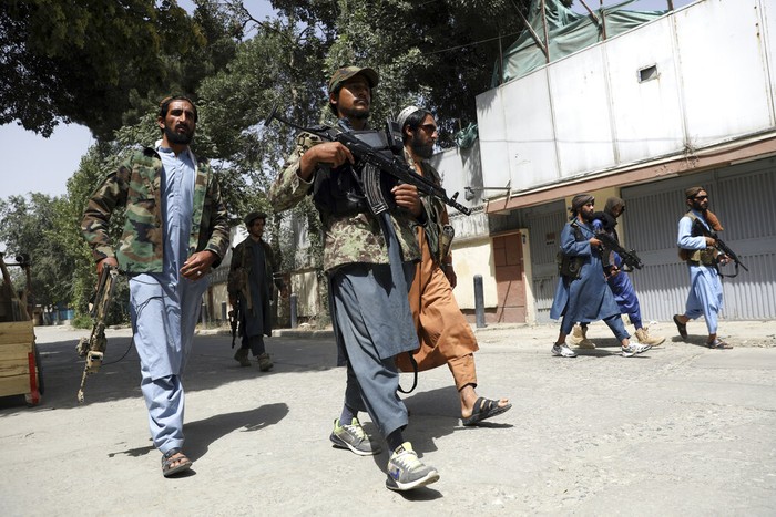 Taliban fighters patrol as two Traffic policemen stand, left, in Kabul, Afghanistan, Thursday, Aug. 19, 2021. The Taliban celebrated Afghanistans Independence Day on Thursday by declaring they beat the United States, but challenges to their rule ranging from running a country severely short on cash and bureaucrats to potentially facing an armed opposition began to emerge. (AP Photo/Rahmat Gul)