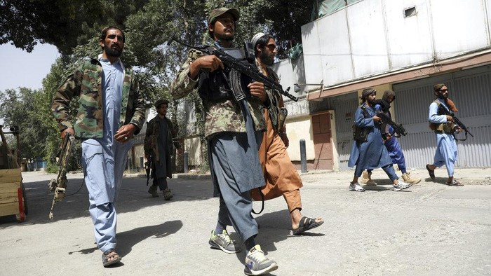Taliban fighters patrol as two Traffic policemen stand, left, in Kabul, Afghanistan, Thursday, Aug. 19, 2021. The Taliban celebrated Afghanistans Independence Day on Thursday by declaring they beat the United States, but challenges to their rule ranging from running a country severely short on cash and bureaucrats to potentially facing an armed opposition began to emerge. (AP Photo/Rahmat Gul)