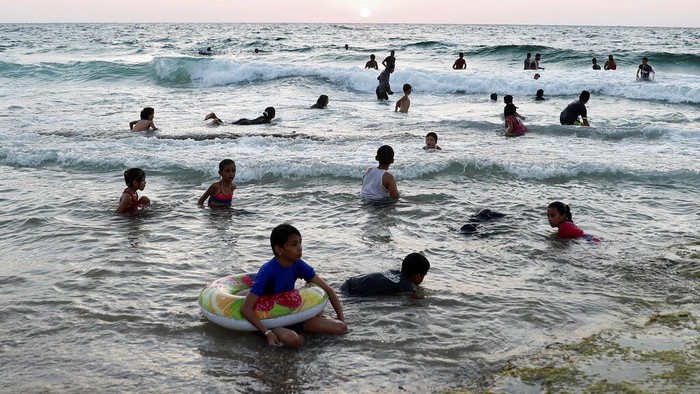Palestinians swim on the Mediterranean Sea during the sunsets near Deir el-Balah refugee camp, central Gaza Strip, Friday, Aug. 20, 2021. (AP Photo/Adel Hana)
