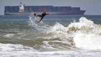 Tampak seorang peselancar menerjang ombak di Pantai Huntington California. 