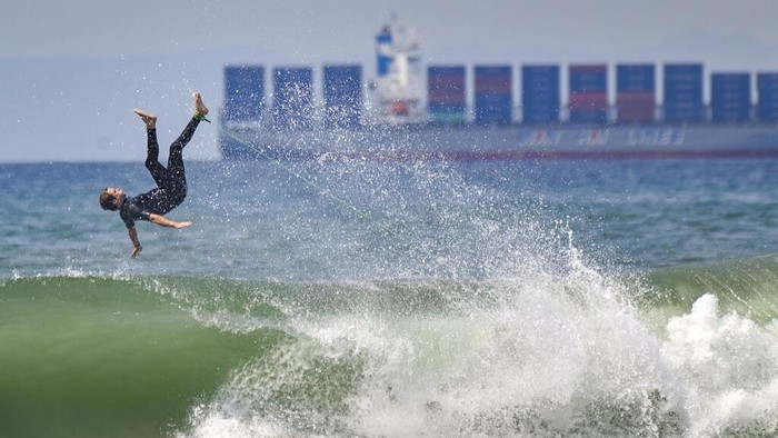 A surfer takes to the waves, north of the pier in Huntington Beach, Calif,  Thursday, Aug. 19, 2021. (Jeff Gritchen/The Orange County Register via AP)