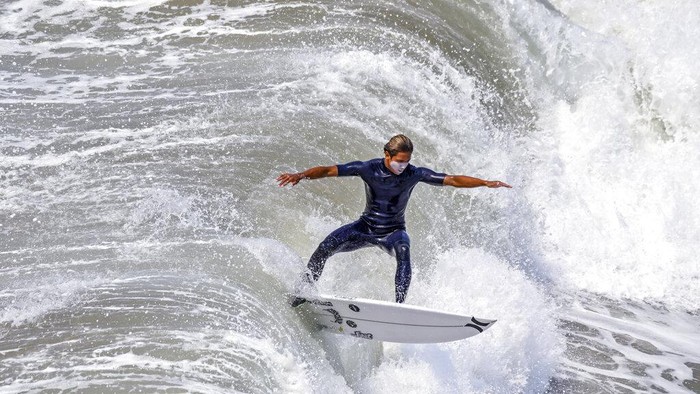 A surfer takes to the waves, north of the pier in Huntington Beach, Calif,  Thursday, Aug. 19, 2021. (Jeff Gritchen/The Orange County Register via AP)