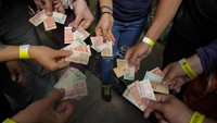 Para wisatawan menunjukkan uang kertas Bolivar lawas yang telah didepresiasi untuk digunakan sebagai tiket yang dapat digunakan untuk menukar makanan selama tur ke area permukiman miskin di Caracas, Venezuela, diselanggarakan.