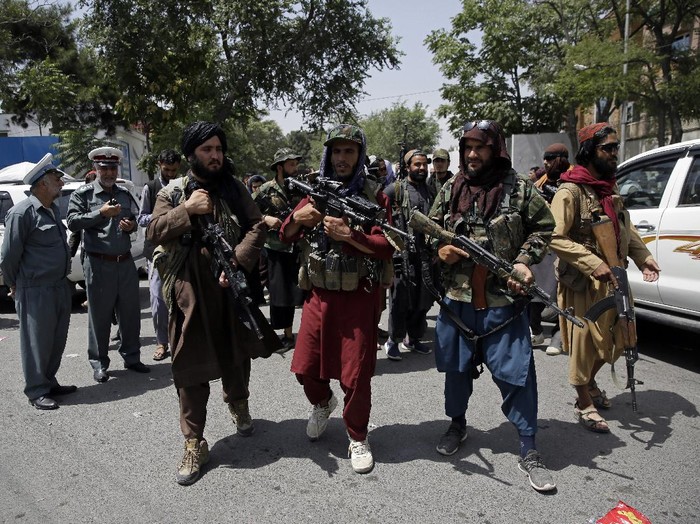 Taliban fighters patrol as two Traffic policemen stand, left, in Kabul, Afghanistan, Thursday, Aug. 19, 2021. The Taliban celebrated Afghanistans Independence Day on Thursday by declaring they beat the United States, but challenges to their rule ranging from running a country severely short on cash and bureaucrats to potentially facing an armed opposition began to emerge. (AP Photo/Rahmat Gul)