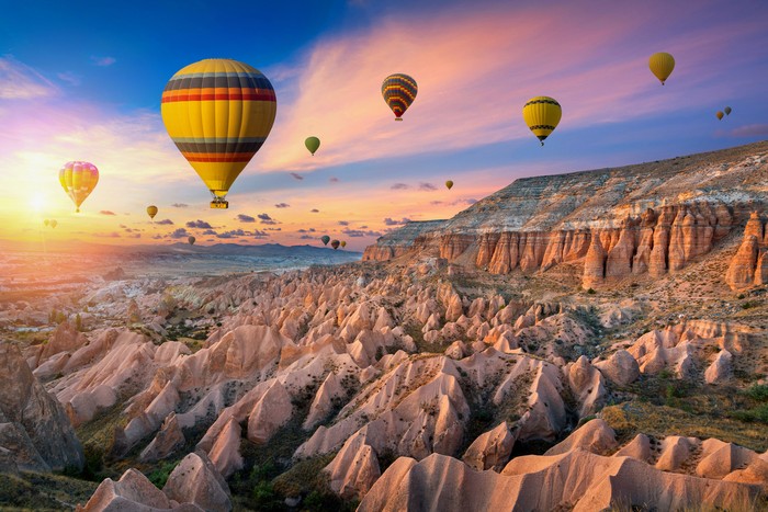 Hot air balloons and Red valley  at sunset in Goreme, Cappadocia in Turkey.