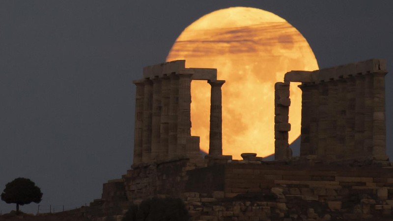 The sturgeon full moon rises behind the ancient Greek marble temple of Poseidon at Cape Sounion, about 70 Km (45 miles) south of Athens, Saturday, Aug. 21, 2021. On Sunday, more than a hundred archeological sites and museums across the country will welcome the public to admire the full moon. (AP Photo/Michael Varaklas)
