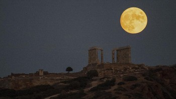 Beginilah penampakan bulan biru atau bulan purnama sturgeon yang muncul di belakang kuil marmer Yunani kuno Poseidon di Cape Sounion, sekitar 70 Km (45 mil) selatan Athena. (AP/Michael Varaklas)