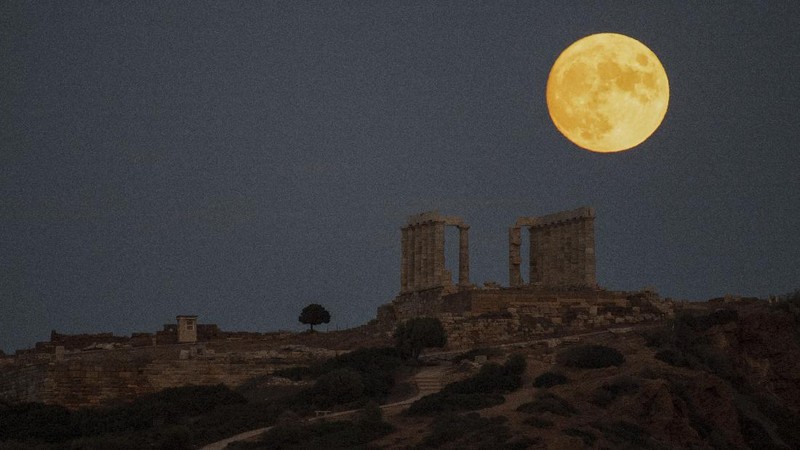 The sturgeon full moon rises behind the ancient Greek marble temple of Poseidon at Cape Sounion, about 70 Km (45 miles) south of Athens, Saturday, Aug. 21, 2021. On Sunday, more than a hundred archeological sites and museums across the country will welcome the public to admire the full moon. (AP Photo/Michael Varaklas)