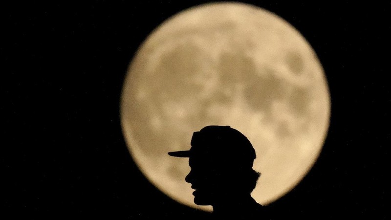 The Art Deco spire of the Kansas City Power and Light building stands against the full moon as it rises beyond the downtown skyline Saturday, Aug. 21, 2021, in Kansas City, Mo. The August full moon is known as the sturgeon moon. (AP Photo/Charlie Riedel)