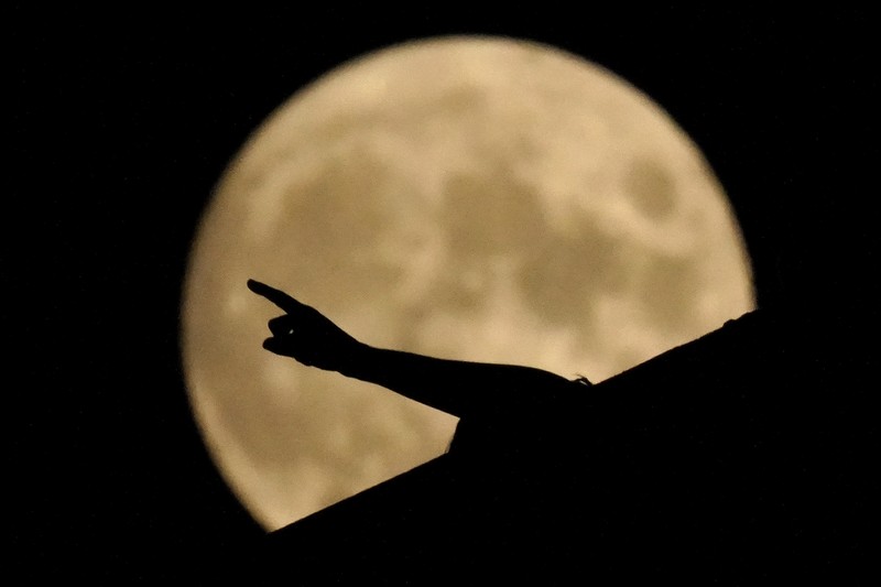 The Art Deco spire of the Kansas City Power and Light building stands against the full moon as it rises beyond the downtown skyline Saturday, Aug. 21, 2021, in Kansas City, Mo. The August full moon is known as the sturgeon moon. (AP Photo/Charlie Riedel)