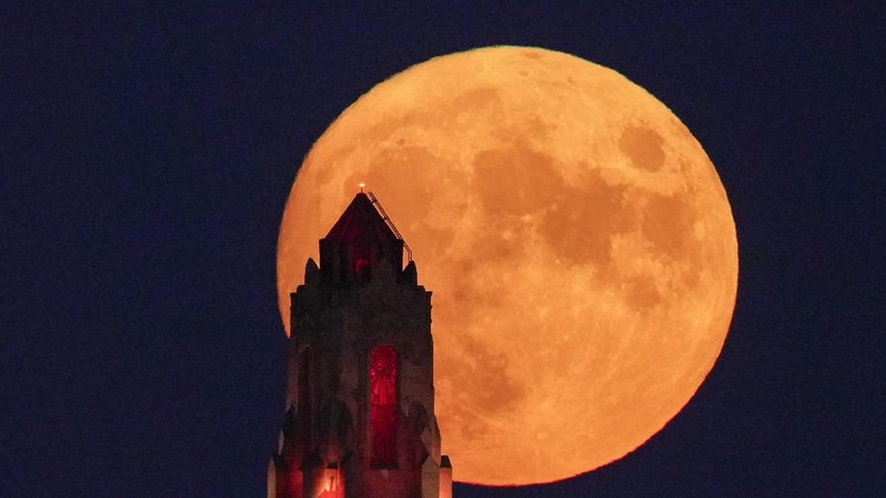 The Art Deco spire of the Kansas City Power and Light building stands against the full moon as it rises beyond the downtown skyline Saturday, Aug. 21, 2021, in Kansas City, Mo. The August full moon is known as the sturgeon moon. (AP Photo/Charlie Riedel)