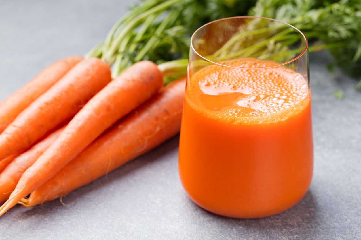 Carrot juice in glass and fresh carrots Healthy food on a grey stone background.