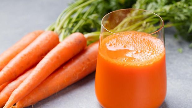 Carrot juice in glass and fresh carrots Healthy food on a gray stone background.