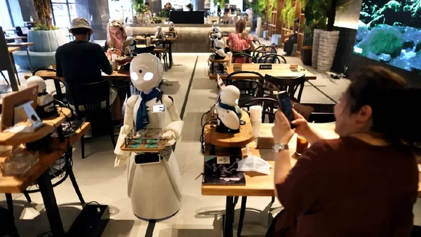Biasanya, saat pelanggan mengobrol dengan pelayan yang mengoperasikan robot, tiga robot lainnya yang lebih besar menyajikan minuman atau menyambut tamu di pintu masuk. Uniknya ada juga robot barista di bar yang bisa membuat kopi. (Behrouz Mehri/AFP)