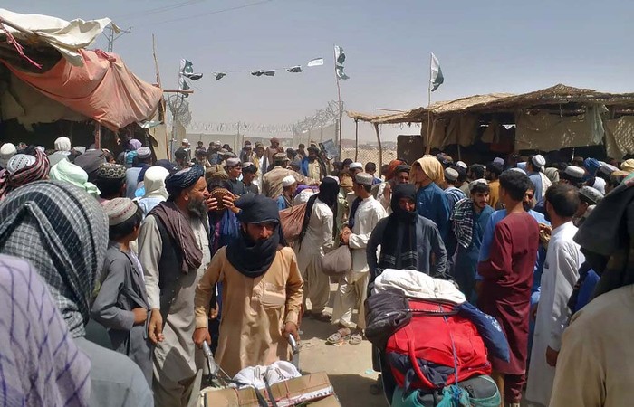 A porter pushes a wheelbarrow carrying a sick Afghan national as he and his relatives enter Pakistan through a border crossing point in Chaman, Pakistan, Monday, Aug. 23, 2021. Chaman is a key border crossing between Pakistan and Afghanistan that normally thousands cross daily along with a steady stream of trucks transporting goods to Afghanistan. (AP Photo/Jafar Khan)