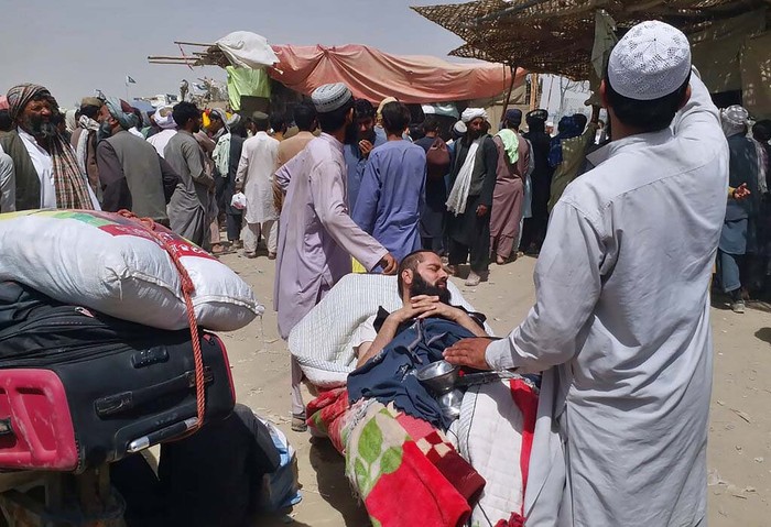 Pakistan Afghanistan A porter pushes a wheelbarrow carrying a sick Afghan national as he and his relatives enter Pakistan through a border crossing point in Chaman, Pakistan, Monday, Aug. 23, 2021. Chaman is a key border crossing between Pakistan and Afghanistan that normally thousands cross daily along with a steady stream of trucks transporting goods to Afghanistan. (AP Photo/Jafar Khan)