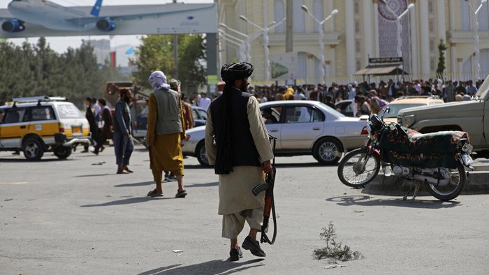 Taliban fighters stand guard in front of the Hamid Karzai International Airport, in Kabul, Afghanistan, Monday, Aug. 16, 2021. Thousands of people packed into the Afghan capitals airport on Monday, rushing the tarmac and pushing onto planes in desperate attempts to flee the country after the Taliban overthrew the Western-backed government. (AP Photo/Rahmat Gul)