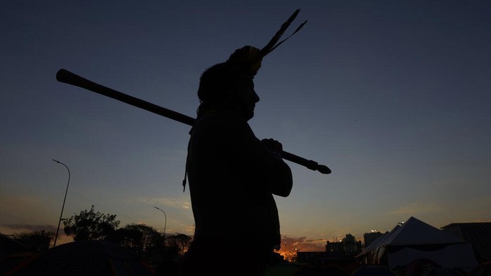 An Indigenous woman paints the face of her companion as Indigenous groups set up the 