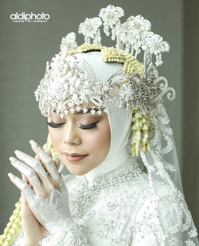 Lesti menggunakan busana adat Sunda di hari akad nikahnya. Penampilannya dilengkapi dengan hijab dan hiasan kepala siger serta ronce melati. Sang makeup artist Bennu Sorumba mengatakan jika makeup Lesti bertema Hollywood Glam. Foto: Dok. Instagram @aldiphoto.