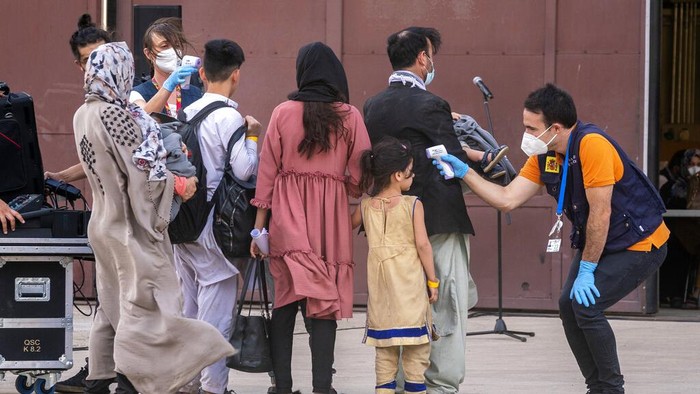 Spanish health minister Carolina Darias talks to an Afghan boy after people disembarked a plane, at the Torrejon military base as part of the evacuation process in Madrid, Monday. Aug. 23, 2021. (AP Photo/Andrea Comas)