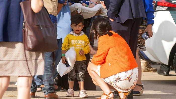 Spanish health minister Carolina Darias talks to an Afghan boy after people disembarked a plane, at the Torrejon military base as part of the evacuation process in Madrid, Monday. Aug. 23, 2021. (AP Photo/Andrea Comas)