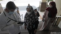 Petugas keamanan membantu pengunjung saat menggunakan aplikasi Peduli Lindungi.