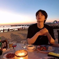 Meskipun tidak menyertakan tempatnya, penggemar langsung tahu lokasinya karena botol minuman bertuliskan Bali. Ahn Jae Hyun membagikan momen makan malam di pinggir pantai bersama seorang teman. Foto: dok Instagram aagbanjh