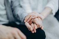 Cropped shot of a young couple sitting on sofa compassionately holding hands in self isolation during Covid-19 health crisis