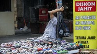 Pedagang kaki lima bersandar sambil menunggu pembeli.
