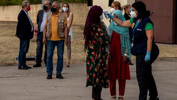 MADRID, SPAIN - AUGUST 24: A worker uses a spot infrared thermometer to measure the body temperature of an Afghan woman, who was evacuated from Kabul, after disembarking from a plane at Torrejon Military Air Base on August 24, 2021 in Madrid, Spain. Madrid has so far evacuated just over 700 people from Afghanistan, with three planes scheduled to arrive today. Spain has been evacuating its nationals and local contractors from Afghanistan through the Dubai airbridge since the Taliban swept to power ten days ago. (Photo by Pablo Blazquez Dominguez/Getty Images)