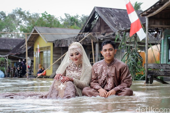 Pasangan pengantin ini viral karena foto pernikahan mereka yang tak biasa yaitu di tengah banjir. Keduanya berpose memakai busana pengantin dan berendam di air banjir. Foto: Dok/@manday_presto.