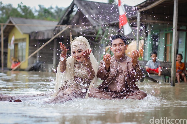 Aksi pengantin foto pernikahan di tengah banjir ini viral setelah diunggah oleh akun TikTok @pengengakinsecure. Dalam video yang diunggah tersebut terlihat area pelaminan yang tergenang banjir setinggi mata kaki orang dewasa. Foto: Dok/@manday_presto.