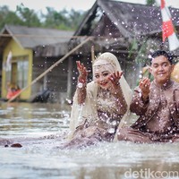 Aksi pengantin foto pernikahan di tengah banjir ini viral setelah diunggah oleh akun TikTok @pengengakinsecure. Dalam video yang diunggah tersebut terlihat area pelaminan yang tergenang banjir setinggi mata kaki orang dewasa. Foto: Dok/@manday_presto.