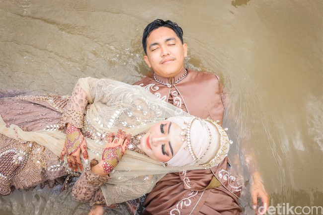 Foto wedding pas banjir wk. Jadi ceritanya klien kami kebanjiran. Katanya mau foto konsep di air. Sorry jelek soalnya masih newbie. Banyak bocor juga karena banyak orang, tulis akun TikTok @pengengakinsecure. Foto: Dok/@manday_presto.