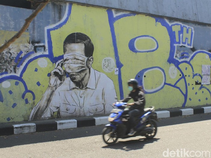 Petugas dari Kecamatan Bandung Wetan masih membersihkan gambar mirip Jokowi dengan mata tertutup masker di Jalan Prabu Dimuntur, Kota Bandung, Kamis (26/8/2021). Terlihat sejumlah petugas masih mengerik kertas sisa gambar tersebut, kemudian memberikan cat putih.