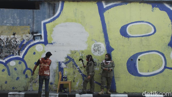 Petugas dari Kecamatan Bandung Wetan masih membersihkan gambar mirip Jokowi dengan mata tertutup masker di Jalan Prabu Dimuntur, Kota Bandung, Kamis (26/8/2021). Terlihat sejumlah petugas masih mengerik kertas sisa gambar tersebut, kemudian memberikan cat putih.