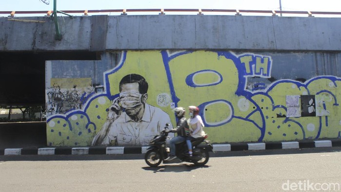 Petugas dari Kecamatan Bandung Wetan masih membersihkan gambar mirip Jokowi dengan mata tertutup masker di Jalan Prabu Dimuntur, Kota Bandung, Kamis (26/8/2021). Terlihat sejumlah petugas masih mengerik kertas sisa gambar tersebut, kemudian memberikan cat putih.