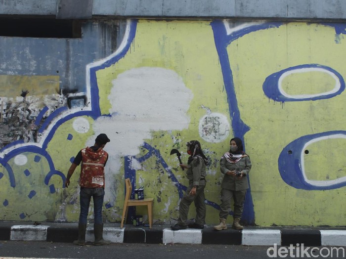 Sejumlah petugas tengah membersihkan sisa mural pria mirip Jokowi di Bandung.