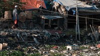 Seorang warga berjalan dibantaran kali yang berasal dari tumpukan sampah. Terlihat dengan jelas bahwa sampah-sampah itu juga memenuhi bibir kali yang dilintasinya.
