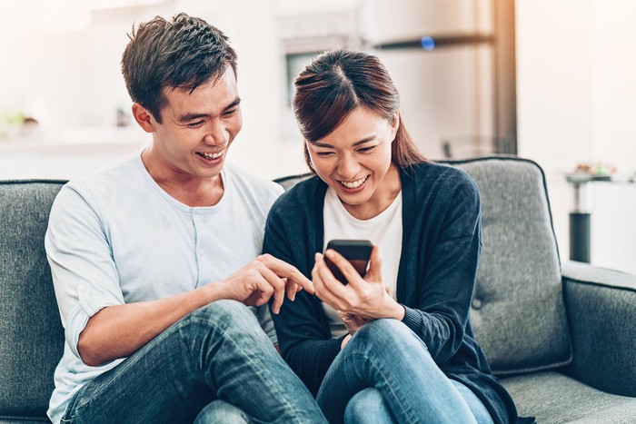 Asian ethnicity couple with smart phone at home