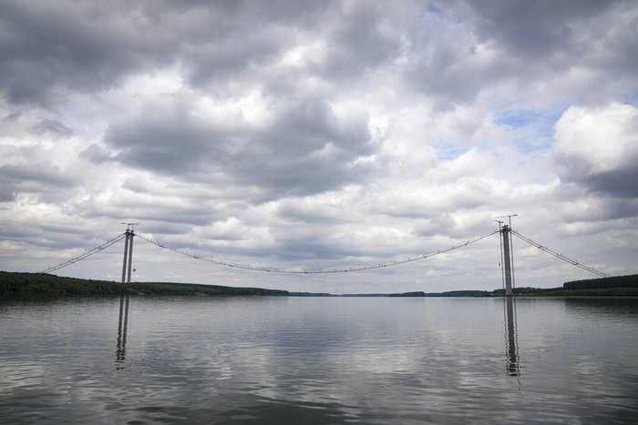 Workers install cables on the structure during a ceremony marking 100 years of diplomatic relations between Japan and Romania, at the construction site of a suspension bridge over the Danube river in Braila, Romania, Thursday, Aug. 26, 2021. The bridge, built by Japanese and Italian companies, with a span of 1,974.3 meters, will be the largest of its kind in Romania and the third in the European union.(AP Photo/Vadim Ghirda)