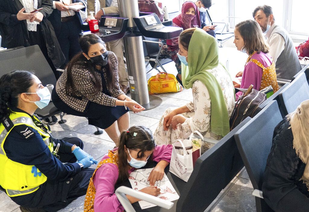 Afghan people who were transported from Afghanistan, walk after disembarking a plane, at the Torrejon military base as part of the evacuation process in Madrid, Monday. Aug. 23, 2021. (AP Photo/Andrea Comas)