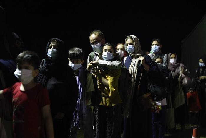 Pengungsi Afghanistan Afghan people who were transported from Afghanistan, walk after disembarking a plane, at the Torrejon military base as part of the evacuation process in Madrid, Monday. Aug. 23, 2021. (AP Photo/Andrea Comas)