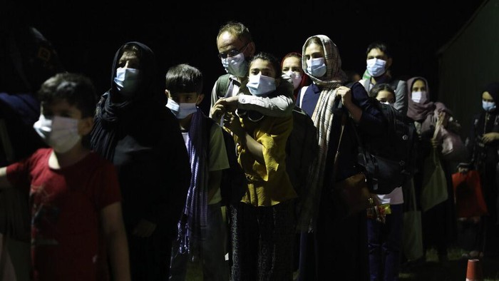 Afghan people who were transported from Afghanistan, walk after disembarking a plane, at the Torrejon military base as part of the evacuation process in Madrid, Monday. Aug. 23, 2021. (AP Photo/Andrea Comas)