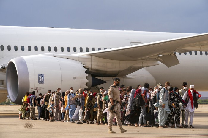 Pengungsi Afghanistan Afghan people who were transported from Afghanistan, walk after disembarking a plane, at the Torrejon military base as part of the evacuation process in Madrid, Monday. Aug. 23, 2021. (AP Photo/Andrea Comas)